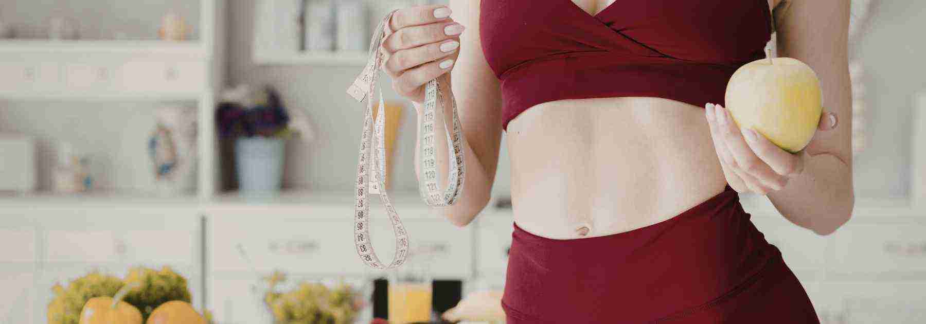 Woman showing off weight loss success in gym wear