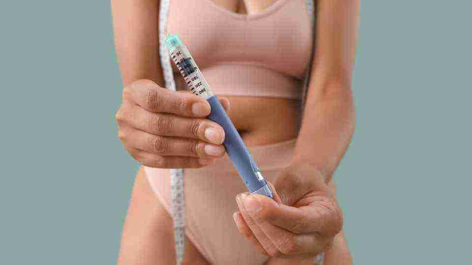 Woman in underwear holding a weight loss injection pen in the foreground
